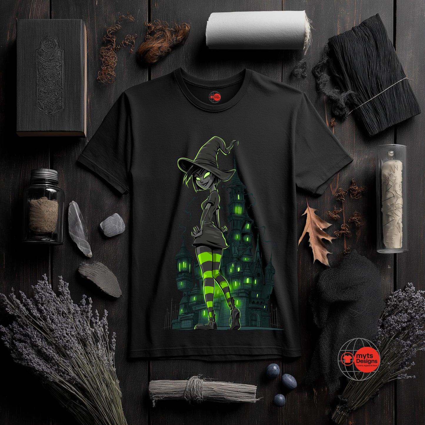 Black t-shirt with witch graphic on a dark wooden surface with Halloween-themed decor.