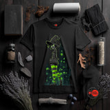 Black t-shirt with witch graphic on a dark wooden surface with Halloween-themed decor.