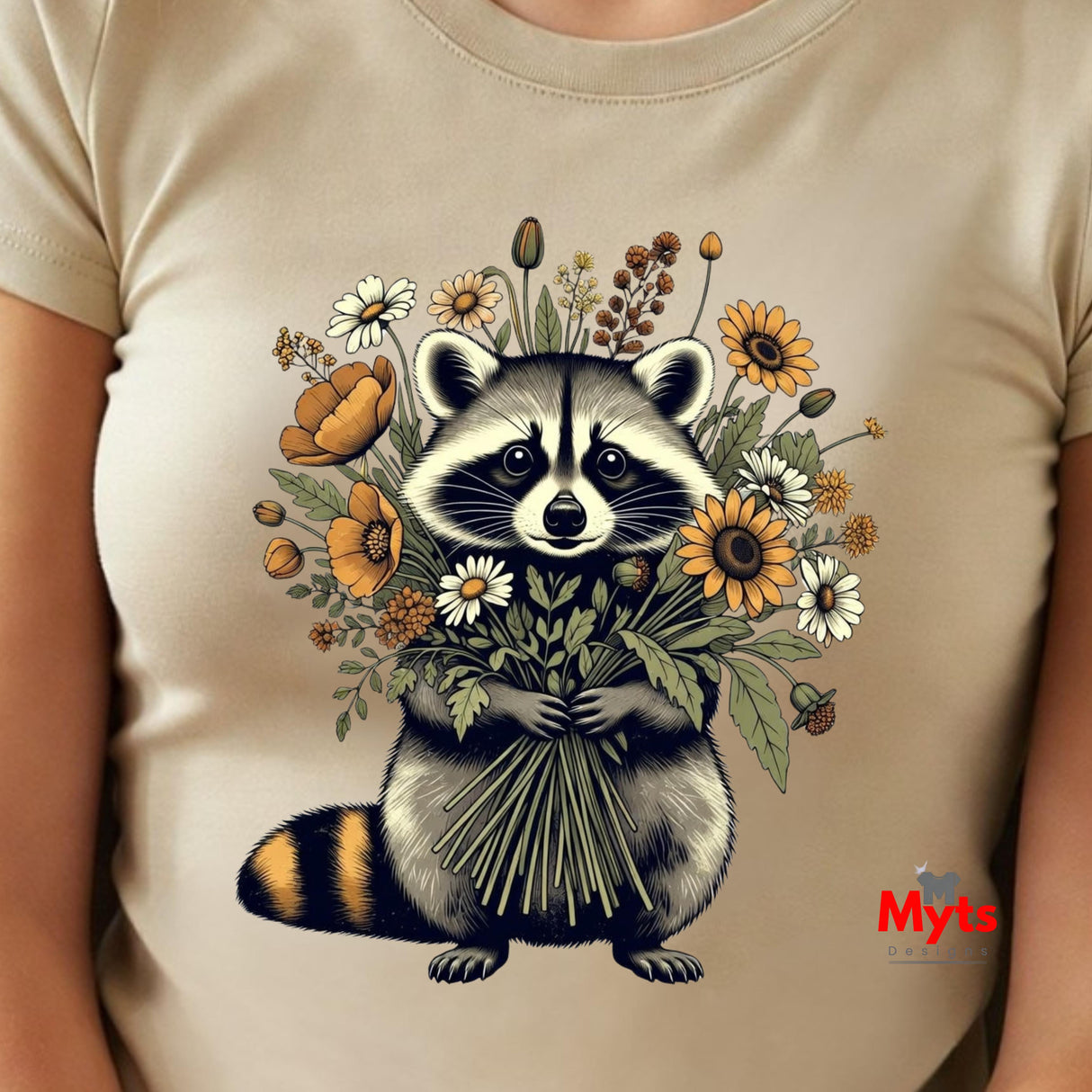 A close-up of a beige t-shirt featuring a detailed graphic of a raccoon holding a bouquet of wildflowers, with a small red 'Myts' logo in the bottom right corner.