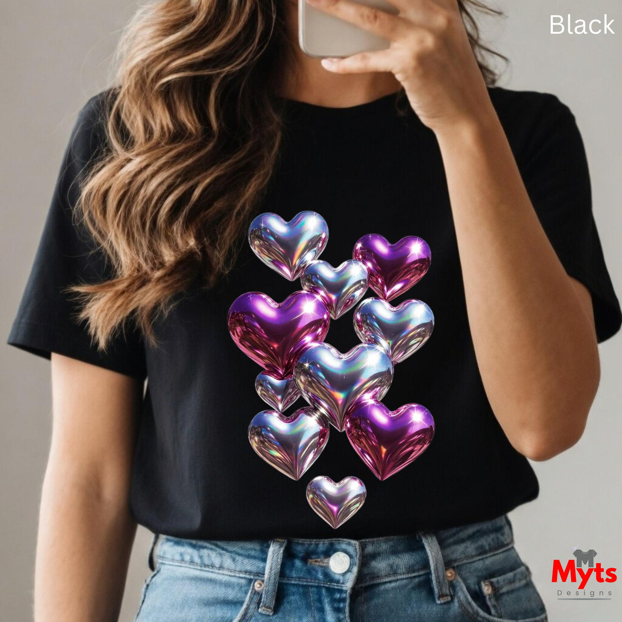 Woman wearing black t-shirt with iridescent holographic heart balloon graphic in shiny pink, purple and blue tones, taking a mirror selfie