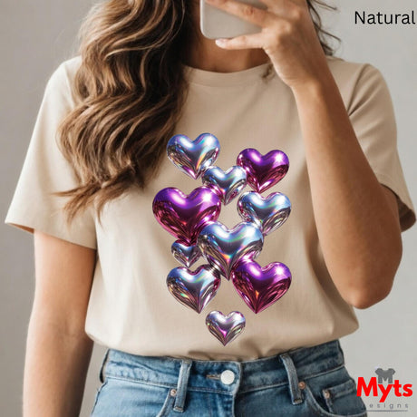 Person wearing a beige t-shirt with iridescent heart designs, holding a phone.