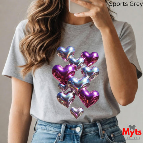Person wearing a gray t-shirt with colorful heart designs and taking a selfie.