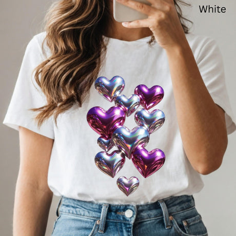 White t-shirt with colorful heart design worn by a person, holding a phone.