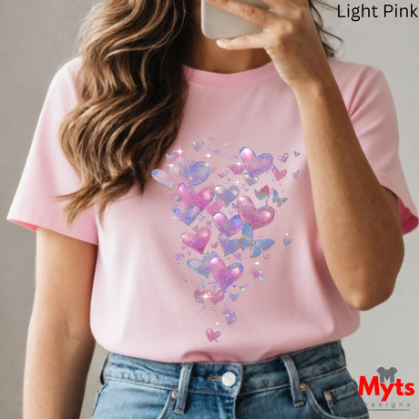 Person wearing a pink t-shirt with colorful heart and butterfly design, holding a phone.
