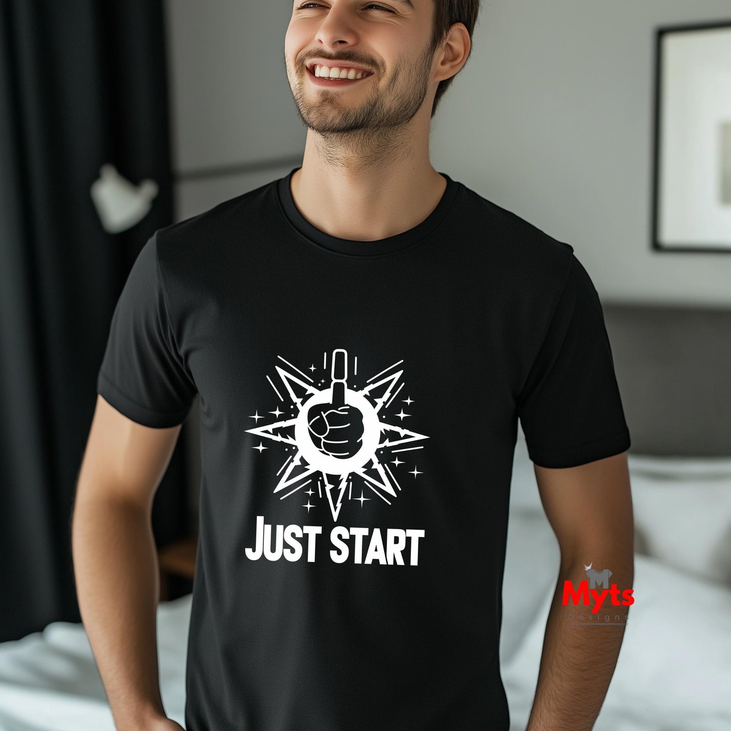 Man wearing a black t-shirt with a white graphic and text 'JUST START' in a bedroom setting.