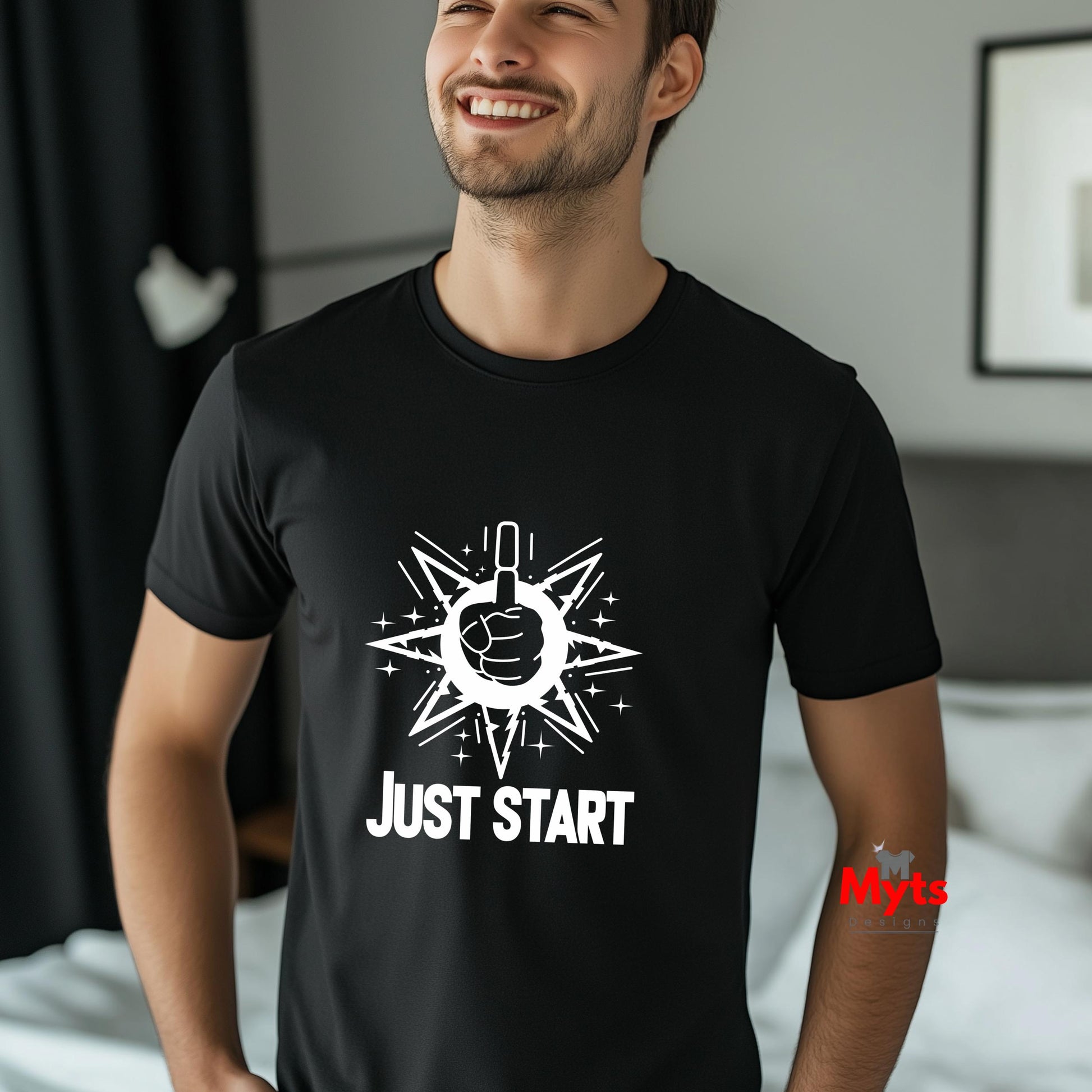 Man wearing a black t-shirt with a white graphic and text 'JUST START' in a bedroom setting.
