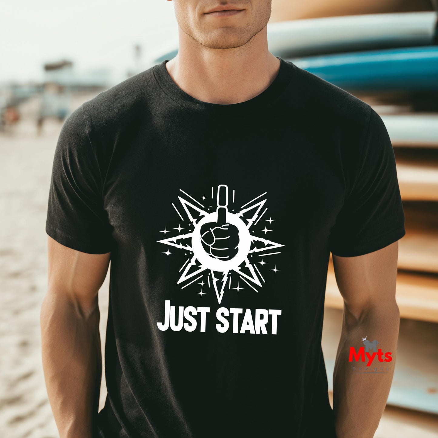 Man wearing a black t-shirt with a white graphic and 'JUST START' text on a beach.