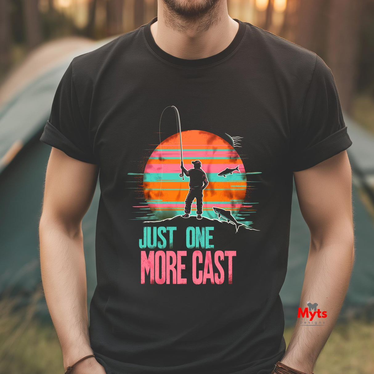 Person wearing a black t-shirt with a fishing graphic and text 'Just One More Cast' in an outdoor setting.