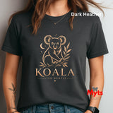 A woman wearing a dark heather charcoal t-shirt with a gold koala graphic and the text 'KOALA LIVE GENTLY' on the front. The image has a watermark 'Myts signs' in the bottom right corner.