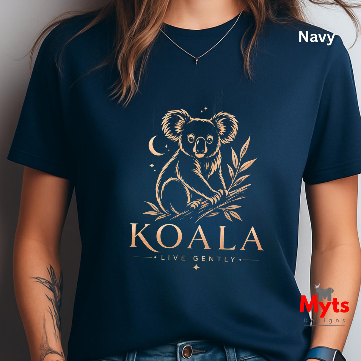 A navy blue short-sleeve t-shirt with a gold line art graphic of a koala, moon, stars, and the text 'KOALA LIVE GENTLY'. The t-shirt is modeled by a person, and the word 'Navy' is printed in white in the top right corner.