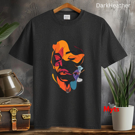 Black t-shirt with colorful graphic design on a wooden surface with plants and a suitcase.