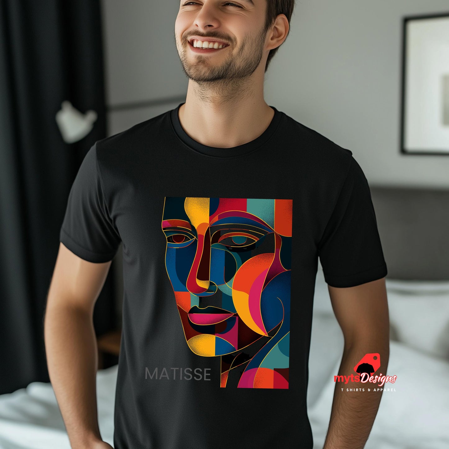 Man wearing a black t-shirt with a colorful face design and 'Matisse' text, standing in a room.