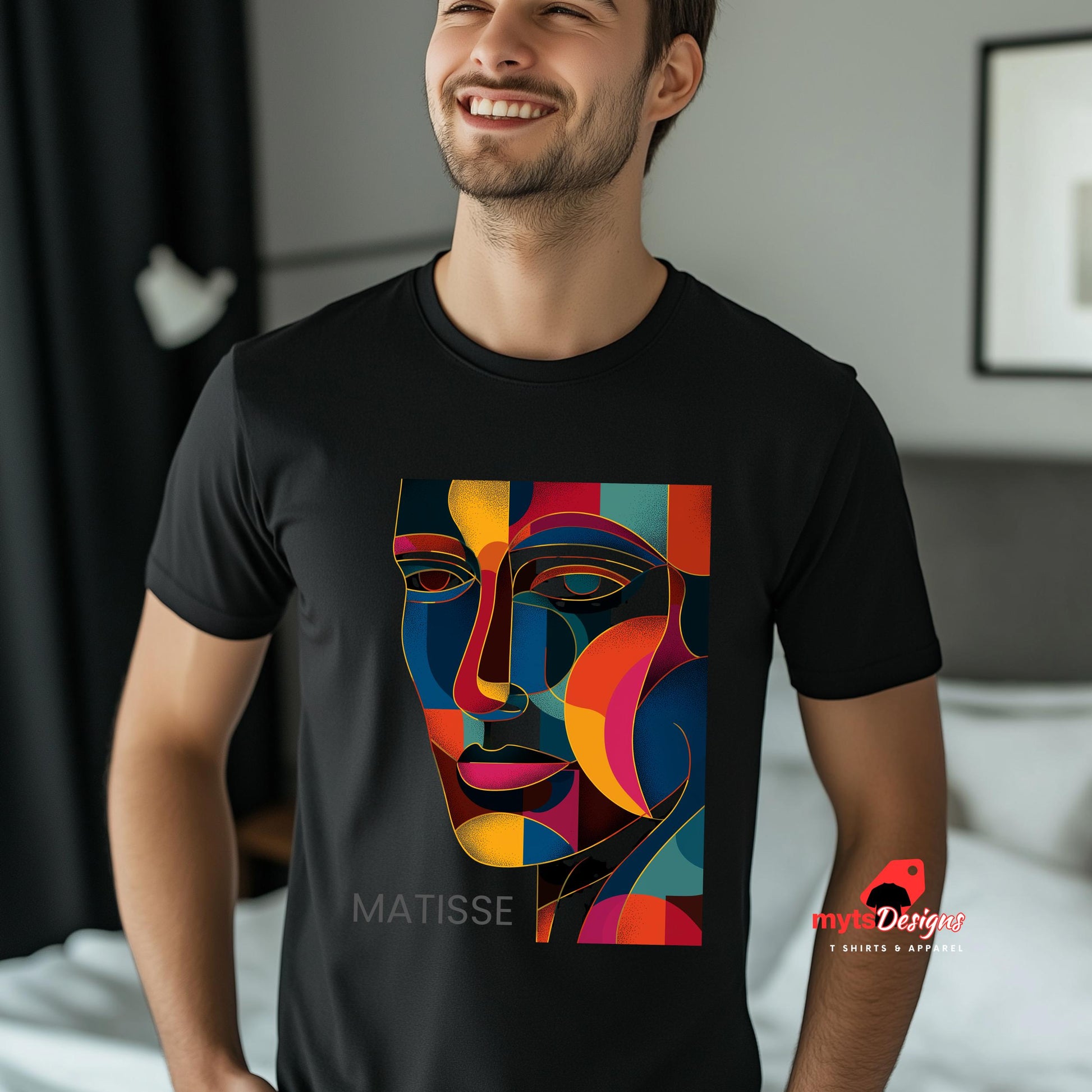 Man wearing a black t-shirt with a colorful face design and 'Matisse' text, standing in a room.