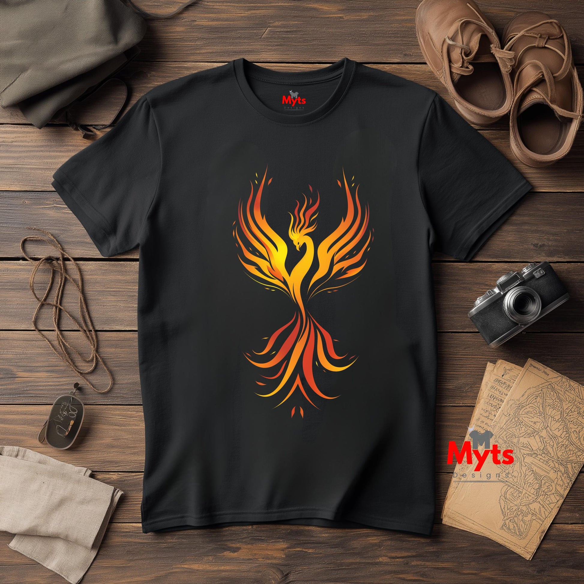 Black t-shirt with a colorful phoenix design on a wooden surface with accessories.