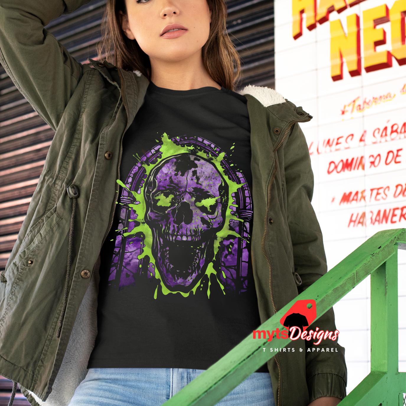 Person wearing a black t-shirt with a purple and green skull design, standing in front of a colorful sign.