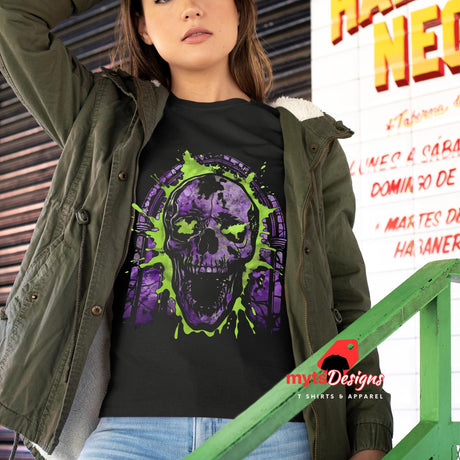 Person wearing a black t-shirt with a purple and green skull design, standing in front of a colorful sign.