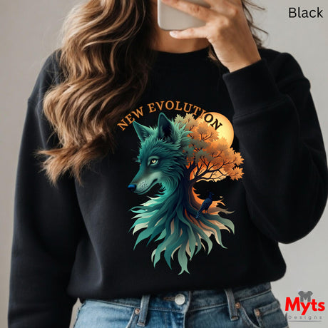 A woman wearing a black crewneck sweatshirt with a detailed graphic of a teal wolf and an orange autumn tree under a yellow sun, with the text 'NEW EVOLUTION' above. She is taking a mirror selfie, and the image has a 'Myts Designs' watermark in the bottom right corner.