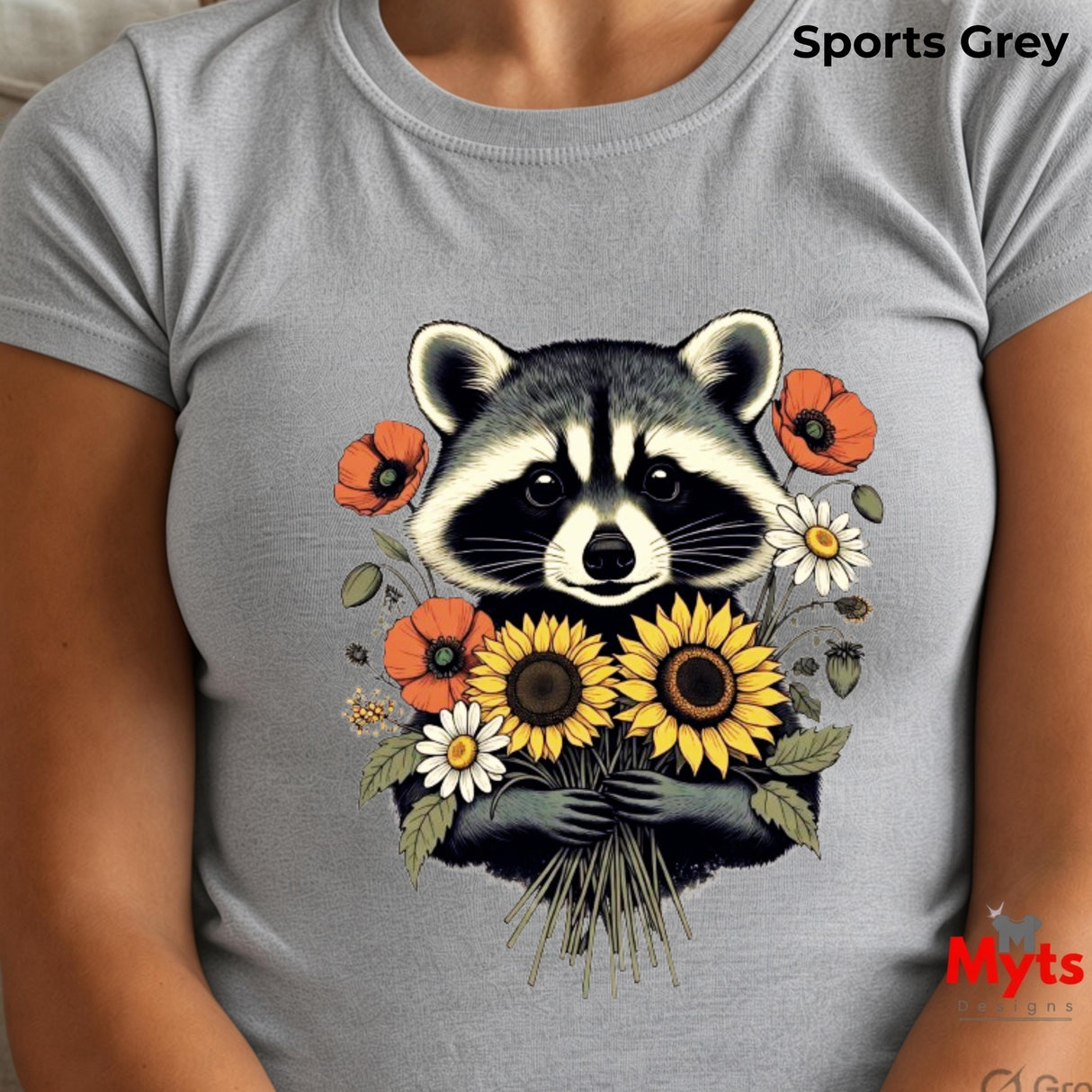 A person wearing a light gray t-shirt with a detailed graphic of a raccoon holding a bouquet of sunflowers, daisies, and poppies. The text 'Sports Grey' is visible in the top right corner, and a 'Myts' brand logo is in the bottom right corner.