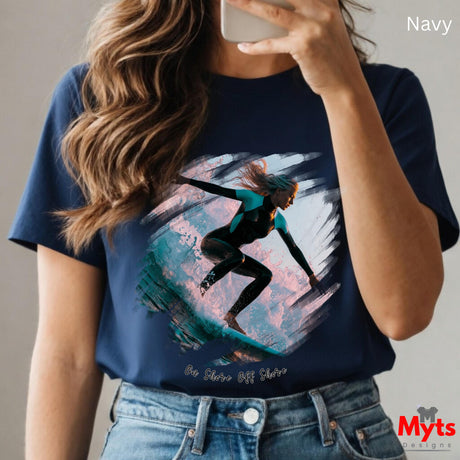 Person wearing a navy t-shirt with a graphic design of a person on a surfboard, holding a phone.