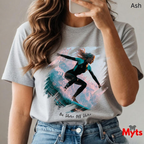 Person wearing a t-shirt with a graphic design of a person on a surfboard, holding a phone.