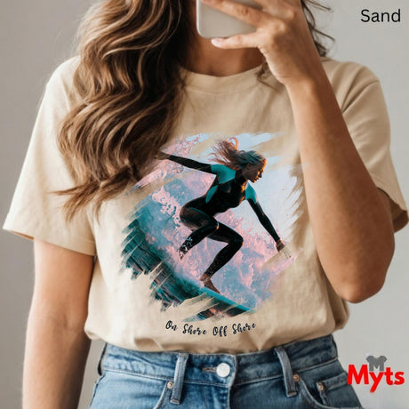 Person wearing a t-shirt with a graphic design of a person on a surfboard, holding a phone.