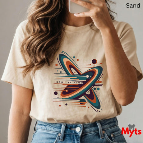 Person wearing a sand t-shirt with a colorful graphic design, holding a phone.