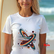 Person wearing a white t-shirt with a colorful graphic design on a beach.