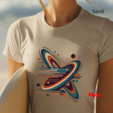 Person wearing a Sand t-shirt with a colorful 'Orbital Flow' design, standing on sand with a blurred background.