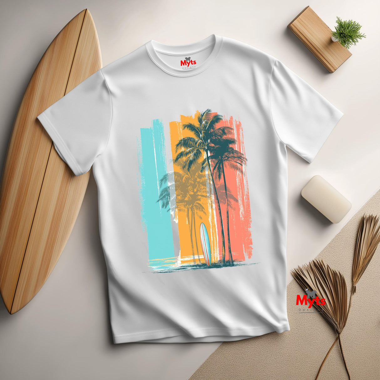 White t-shirt with a colorful palm tree design on a light surface with a surfboard and decor items.