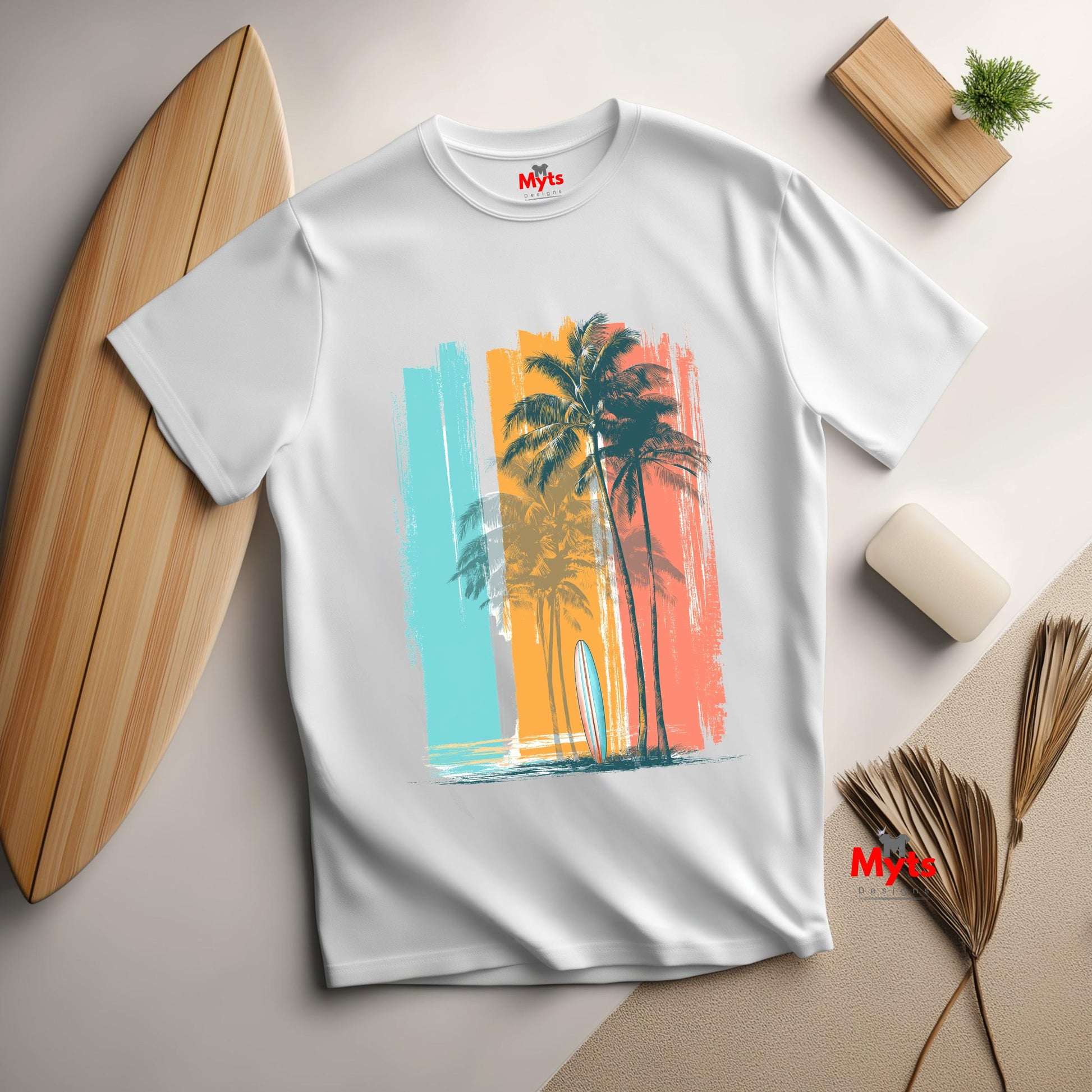 White t-shirt with a colorful palm tree design on a light surface with a surfboard and decor items.