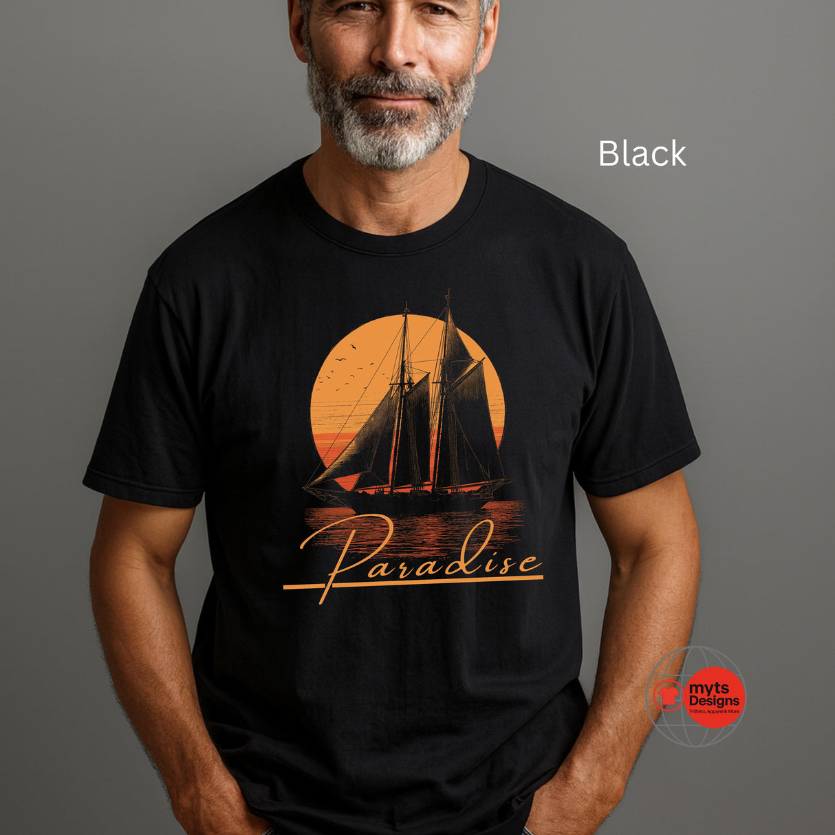 Man wearing a black t-shirt with a sailboat design and 'Paradise' text on a gray background