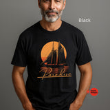 Man wearing a black t-shirt with a sailboat design and 'Paradise' text on a gray background