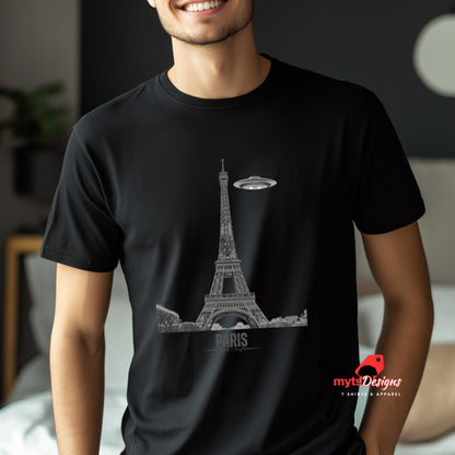 Front view of a black soft casual tee featuring a whimsical graphic of the Eiffel Tower with a retro‑style spaceship orbiting it, worn by a young man in a bedroom setting.