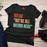 A flat lay view of a black Retro-style casual tee featuring bold distressed vintage typography reading “Relax — We’re All Weird Here,” printed on ultra-soft Gildan 64000 cotton.