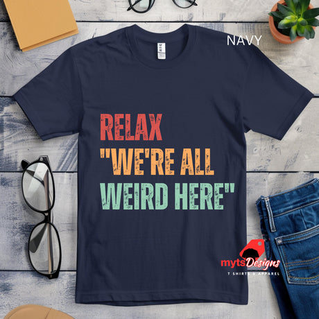 A flat lay view of a navy colored Retro-style casual tee featuring bold distressed vintage typography reading “Relax — We’re All Weird Here,” printed on ultra-soft Gildan 64000 cotton.