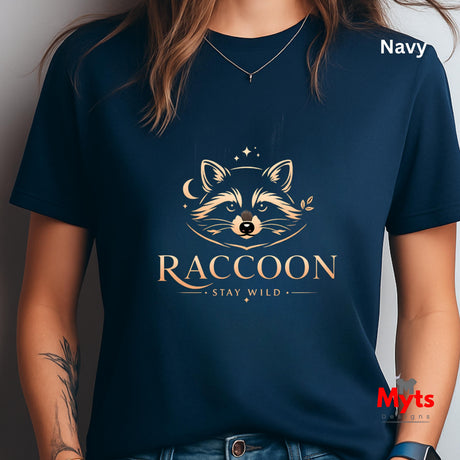 A navy blue short-sleeve t-shirt worn by a model, featuring a gold graphic of a raccoon face with stars and the text 'RACCOON STAY WILD'. The word 'Navy' is printed in white in the top right corner, and a red 'Myts Designs' logo is visible in the bottom right corner.