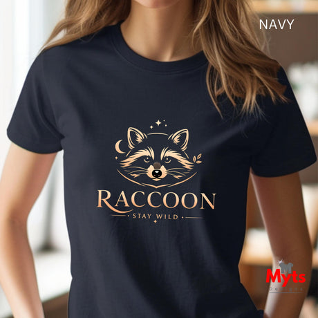 A woman wearing a navy blue short-sleeve t-shirt with a gold graphic of a raccoon's face and the text 'RACCOON STAY WILD'. The image has 'NAVY' text in the top right corner and a 'Myts' watermark in the bottom right.