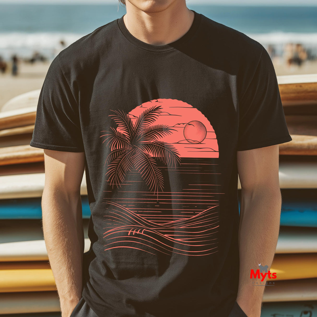 Person wearing a black t-shirt with a red palm tree and sunset design, standing in front of stacked surfboards on a beach.