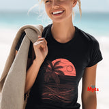 Woman wearing a black t-shirt with a pink palm tree design, standing on a beach.