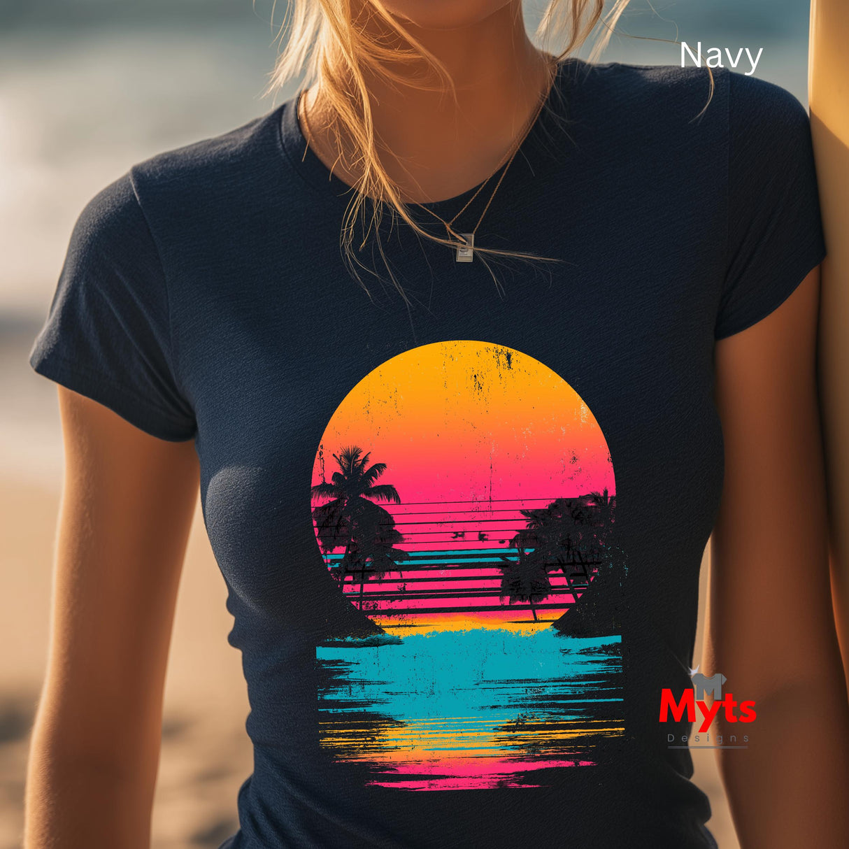 Person wearing a navy t-shirt with a colorful sunset design on a beach.