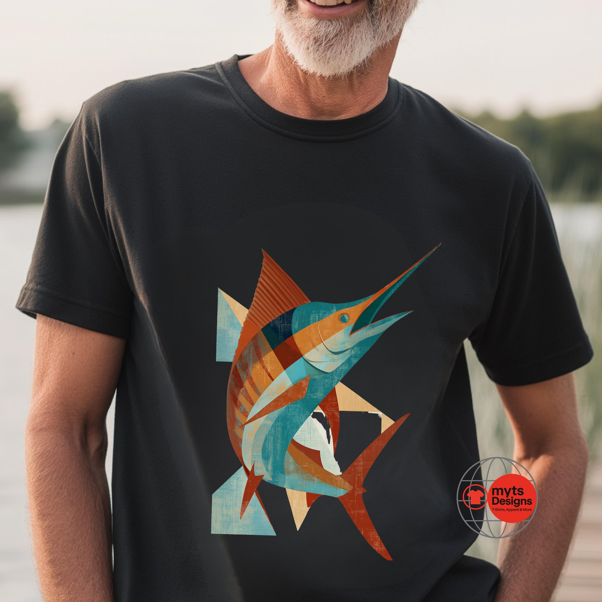 Man wearing a black t-shirt with a colorful fish design by a body of water.