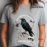 Gray t-shirt with a crow design and text, worn by a person.