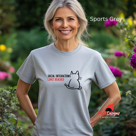 “Sports grey T-shirt worn by a senior woman standing in a cottage garden, with a minimal line art cat and text reading ‘Social Interactions Limit Reached’ in bold black and red font, humorous introvert design from MytsDesigns.com”