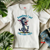 White t-shirt with cartoon donkey graphic and text 'Sometimes I just think funny things' on a beige surface with green leaves.