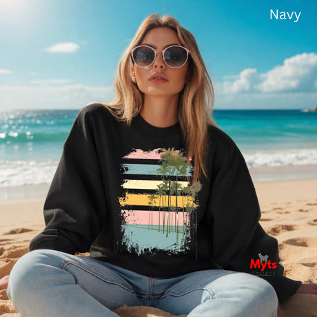 Woman wearing a black sweatshirt with a colorful design sitting on a beach.