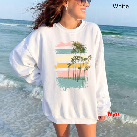 Woman wearing a white sweatshirt with a palm tree design on a beach