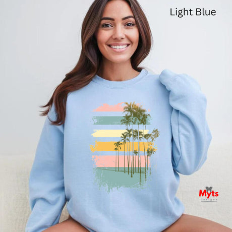 Woman wearing a light blue sweatshirt with a palm tree design, sitting against a plain background.