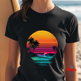 Black t-shirt with a colorful sunset and palm tree design worn by a person on a beach.