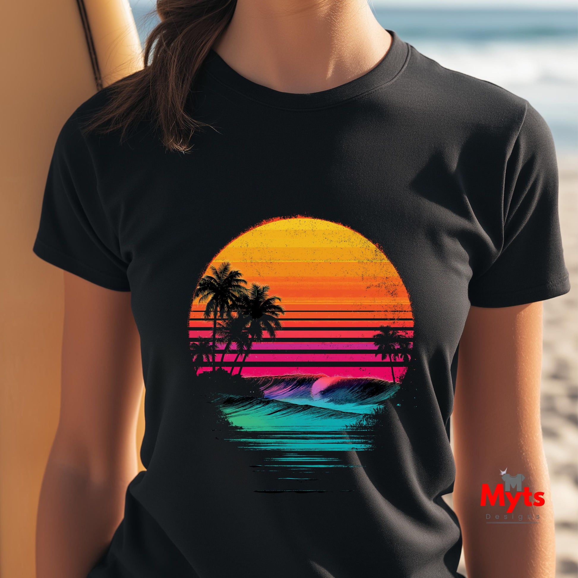 Black t-shirt with a colorful sunset and palm tree design worn by a person on a beach.