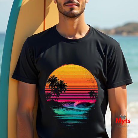 Person wearing a black t-shirt with a colorful sunset and palm tree design, standing by a surfboard on a beach.